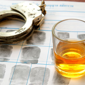 A glass of alcohol and handcuffs on a table - Law Office of E. Michael Linscheid