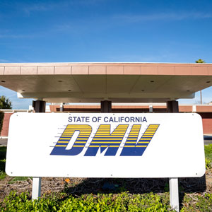 A white sign with the (DMV) logo and the words "State of California" in blue and yellow - Law Office of E. Michael Linscheid